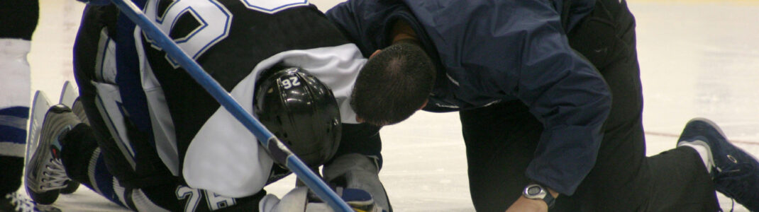 An injured hockey player is attended to on the ice by the team doctor.